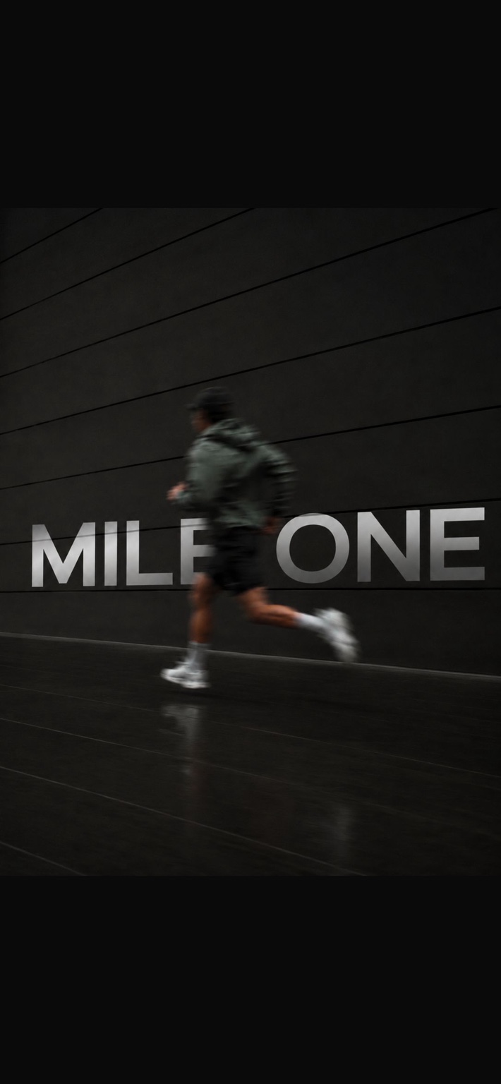 A runner in motion against a dark Mile One wall